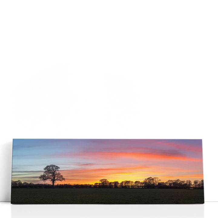 Black silhouette wall art with tree in orange sky